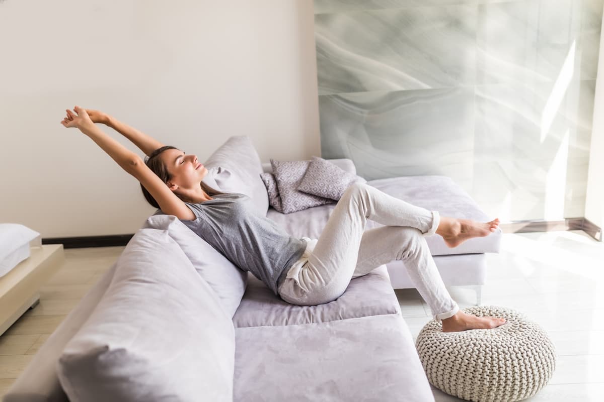 Mujer relajada y fresca en el sofá de su salón, con una temperatura agradable en casa